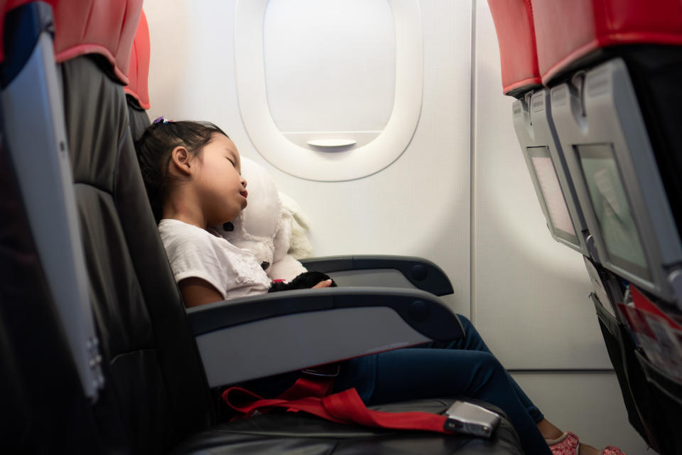 Little girl hugging her doll and sleeping during the flight