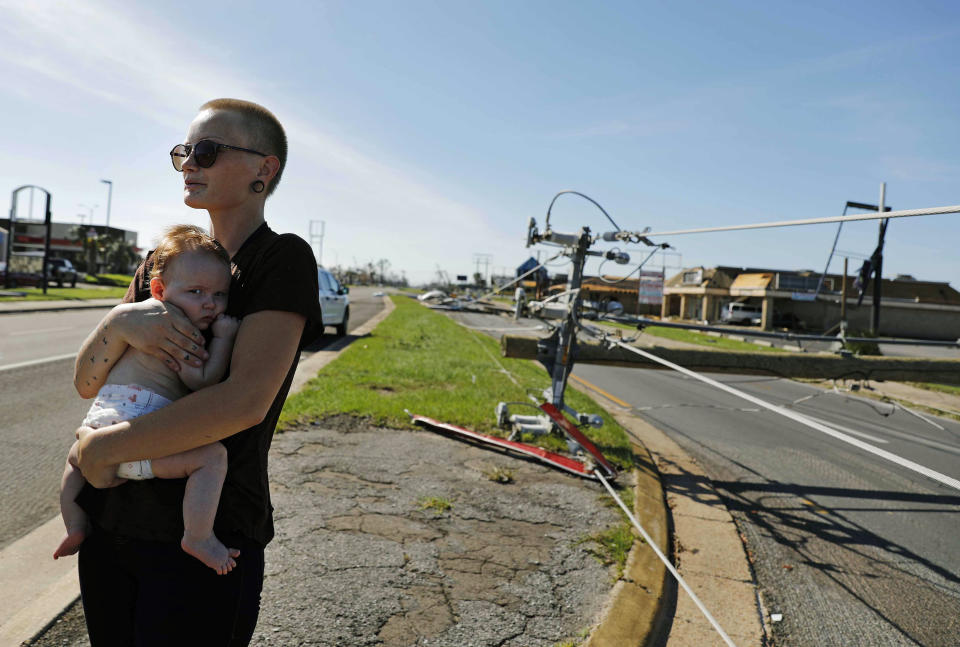 Kylie Strampe carga a su hija de cuatro meses, Lola, mientras observa el jueves 11 de octubre de 2018 el daño causado por el huracán Michael en Callaway, Florida. (AP Foto/David Goldman)