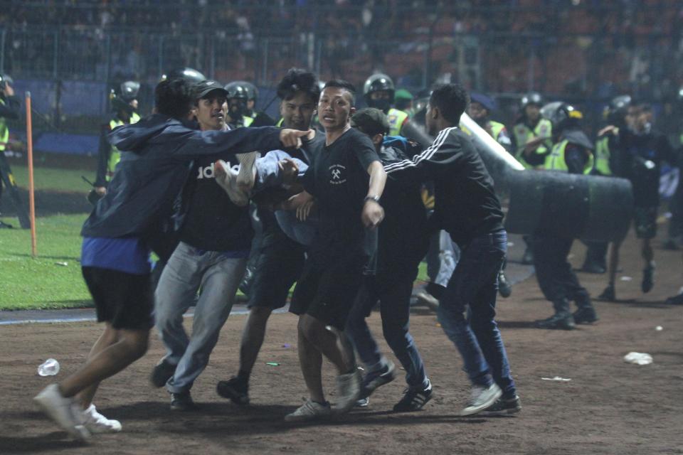 Supporters evacuate a man hit by tear gas fired by police during the riot after the league BRI Liga 1 football match between Arema vs Persebaya, in Indonesia (via REUTERS)