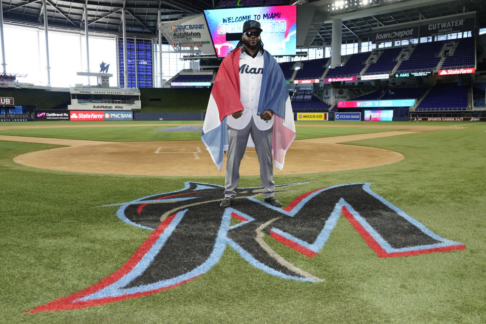 Pitcher Johnny Cueto poses for a photograph draped with the flag of the Dominican Republic, after signing a contract with the Miami Marlins baseball team, Thursday, Jan. 19, 2023, in Miami. Cueto signed a one-year contract with the Marlins with a club option for 2024. (AP Photo/Lynne Sladky)