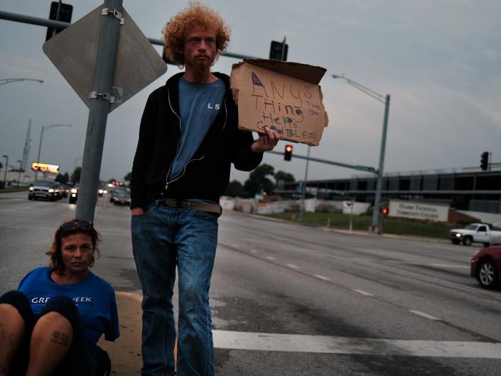 Mathew and his girlfriend Vicki, who are both homeless, panhandle on a street on August 05, 2021 in Springfield, Missouri.