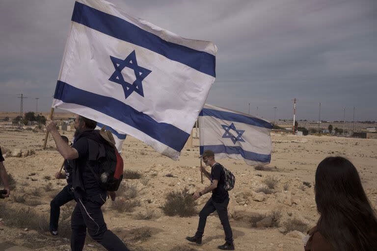 Personas caminan hacia el cruce fronterizo de Nitzana con Egipto en el sur de Israel, el lunes 12 de febrero de 2024, protestando contra la entrada de ayuda humanitaria a Gaza hasta que se liberen a todos los rehenes.