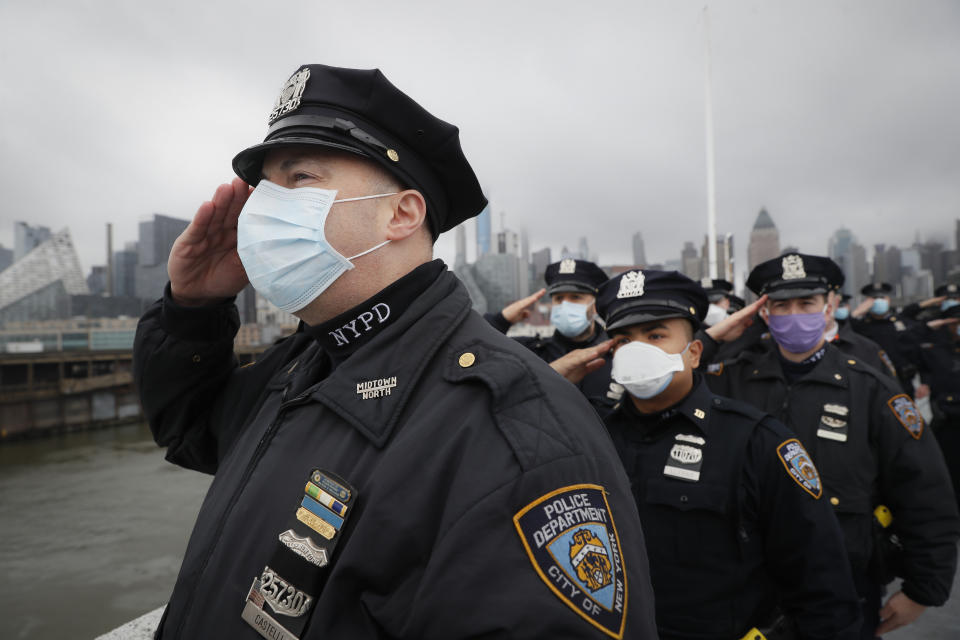 NYPD officers salute the USNS Naval Hospital Ship Comfort as it is pushed out into the Hudson River by tugboats, Thursday, April 30, 2020, in the Manhattan borough of New York. (AP Photo/John Minchillo)