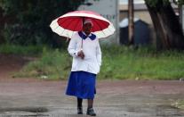 Faithful walks holding an umbrella on her way to church in Soweto