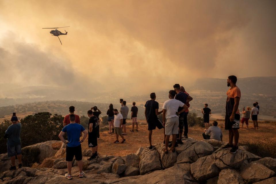 A firefighting helicopter drops water on a wildfire in Mandra, Greece (REUTERS)