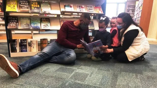 Marques Crosby, left, reads with his wife, Angelica, and his daughters Juliana, then 4, and Gabrielle, 2, at the Medway Public Library in April 2021. Marques Crosby was part of an effort to have Medway change from Columbus Day to Indigenous Peoples' Day.