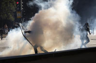 An anti-government demonstrator is engulfed by a cloud of teargas during clashes in Sao Paulo, Brazil, Sunday, May 31, 2020. Police used tear gas to disperse anti-government protesters in Brazil's largest city as they began to clash with small groups loyal to President Jair Bolsonaro. (AP Photo/Andre Penner)