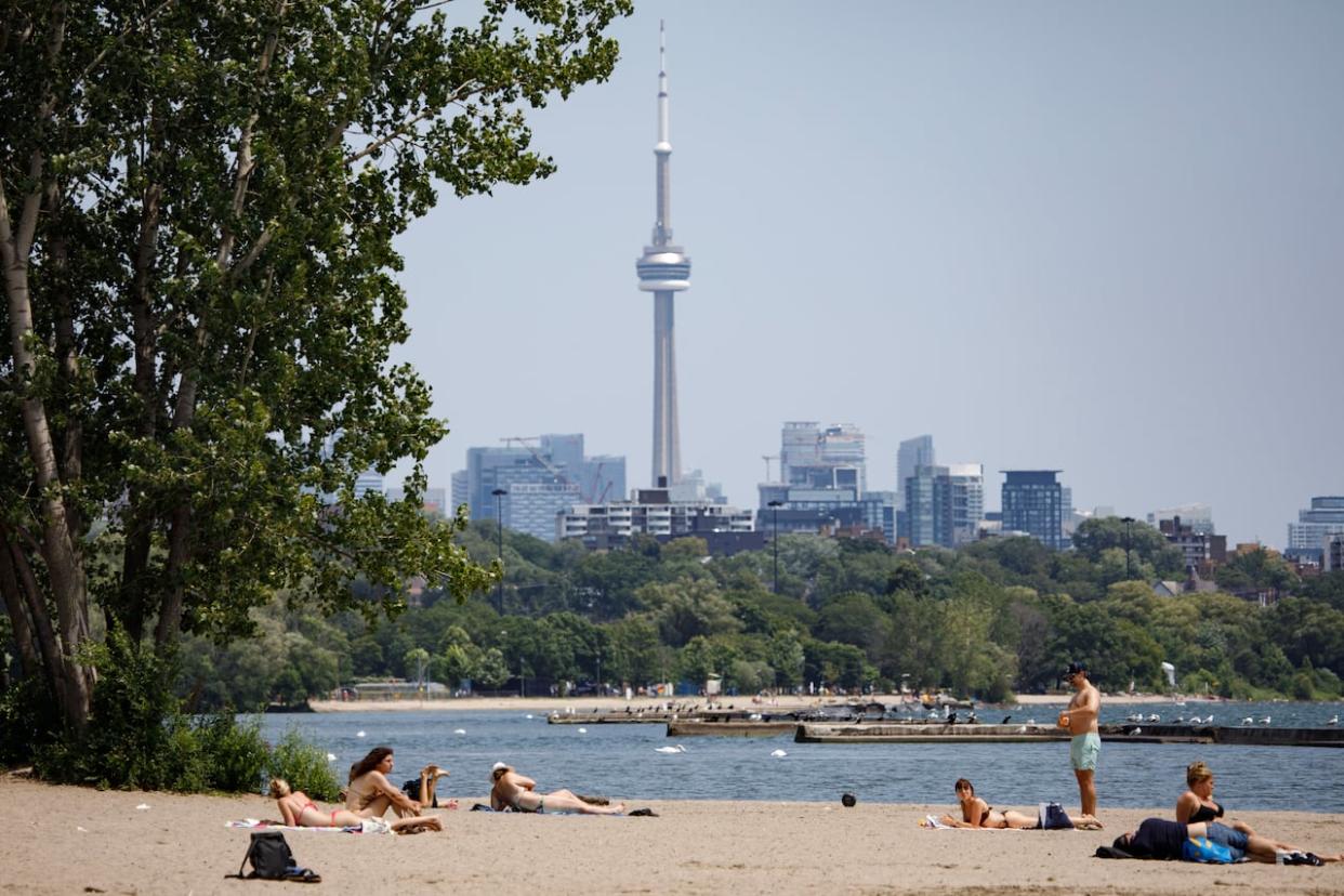 People are photographed during a warm day at Sunnyside Park in Toronto on July 11, 2023. Toronto is about to be hit with a three-day heat wave this week, starting Sunday, Environment Canada says. (Alex Lupul/CBC - image credit)