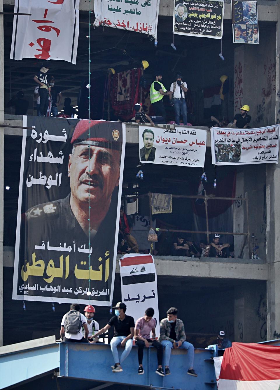 Posters of protesters who have died in anti-government demonstrations and a poster of Lt. Gen. Abdul-Wahab al-Saadi, left, the former commander of the country's elite counterterrorism forces whose dismissal sparked protests about a month ago, hang on a building near Tahrir Square, in Baghdad, Iraq, Sunday, Nov. 3, 2019. (AP Photo/Hadi Mizban)