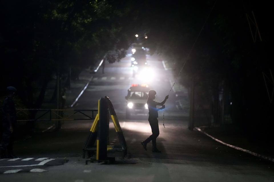 A government soldier opens a gate to a motorcade which is believed to be conveying Sri Lanka's former president Gotabaya Rajapaksa after his arrival at the Bandaranaike International airport in Colombo, Sri Lanka, Saturday, Sept. 3, 2022. Gotabaya Rajapaksa, who fled the country in July after tens of thousands of protesters stormed his home and office in a display of anger over the country's economic crisis, has returned to the country after seven weeks. (AP Photo/Eranga Jayawardena)