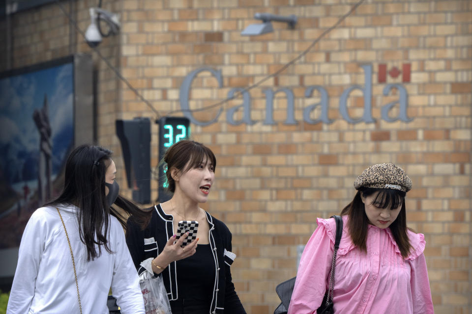 People walk across an intersection near the Canadian Embassy in Beijing, Saturday, Sept. 25, 2021. Two Canadians detained in China on spying charges were released from prison and flown out of the country on Friday, Prime Minister Justin Trudeau announced Friday, hours after a top executive of Chinese communications giant Huawei Technologies resolved criminal charges against her in a deal with the U.S. Justice Department. (AP Photo/Mark Schiefelbein)