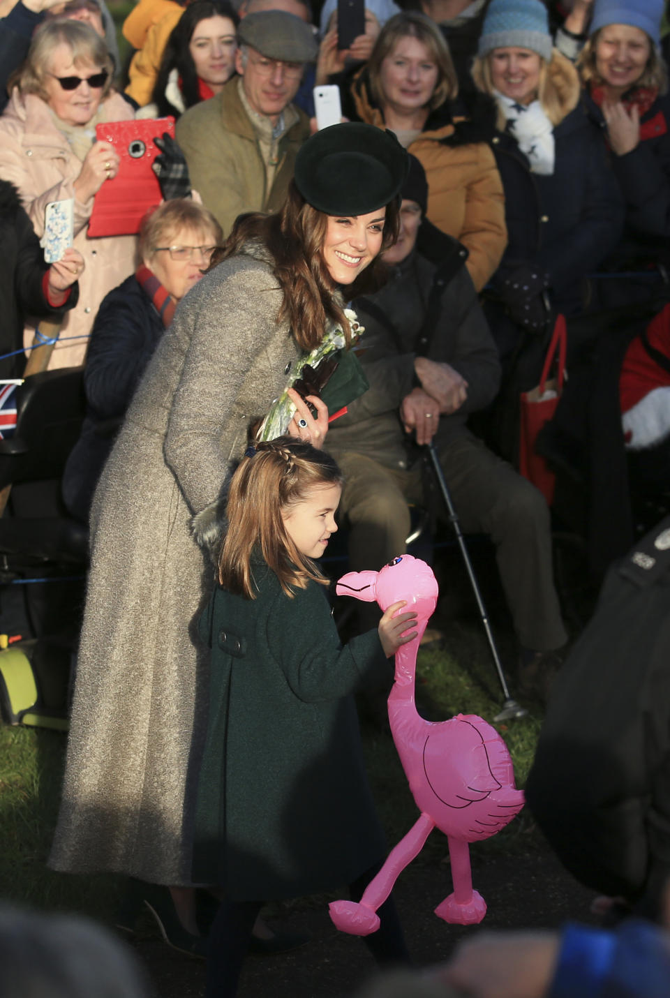 Britain's Catherine, Duchess of Cambridge, center left, speaks with her daughter Princess Charlotte as she holds a pink flamingo while greeting the public outside the St Mary Magdalene Church in Sandringham in Norfolk, England, Wednesday, Dec. 25, 2019. (AP Photo/Jon Super)