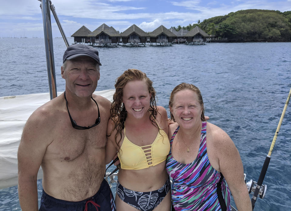 Kristen Pankratz, center, poses with her parents David and Anne on their yacht Amazing Grace in Tahiti on April, 23, 2020. Pankratz gave up her advertising job in Dallas and set sail with her parents in January. But now, along with hundreds of other sailors, the family finds themselves stranded in paradise. They made it as far as Tahiti in remote French Polynesia, one of the last places to offer refuge as borders slammed shut. (Kristen Pankratz via AP)