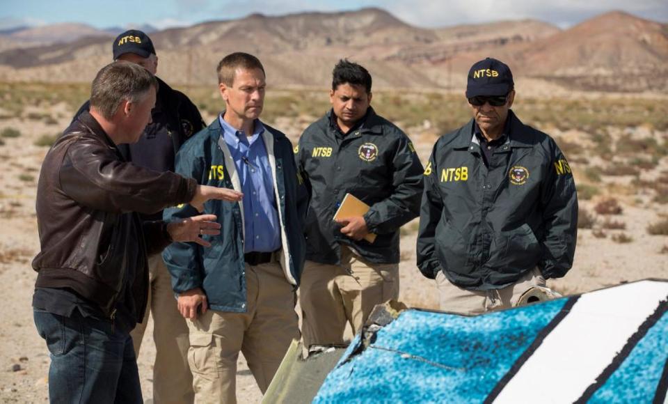 In this Nov. 1, 2014, photo provided by the National Transportation Safety Board, Virgin Galactic pilot Todd Ericson, left, talks with NTSB Acting Chairman Christopher A. Hart, right, at SpaceShipTwo accident site with investigators in Mojave, Calif. The cause of Friday&#39;s crash of Virgin Galactic&#39;s SpaceShipTwo has not been determined, but investigators found the &quot;feathering&quot; system, which rotates the tail to create drag, was activated before the craft reached the appropriate speed, National Transportation Safety Board Acting Chairman Christopher Hart said. (AP Photo/NTSB)