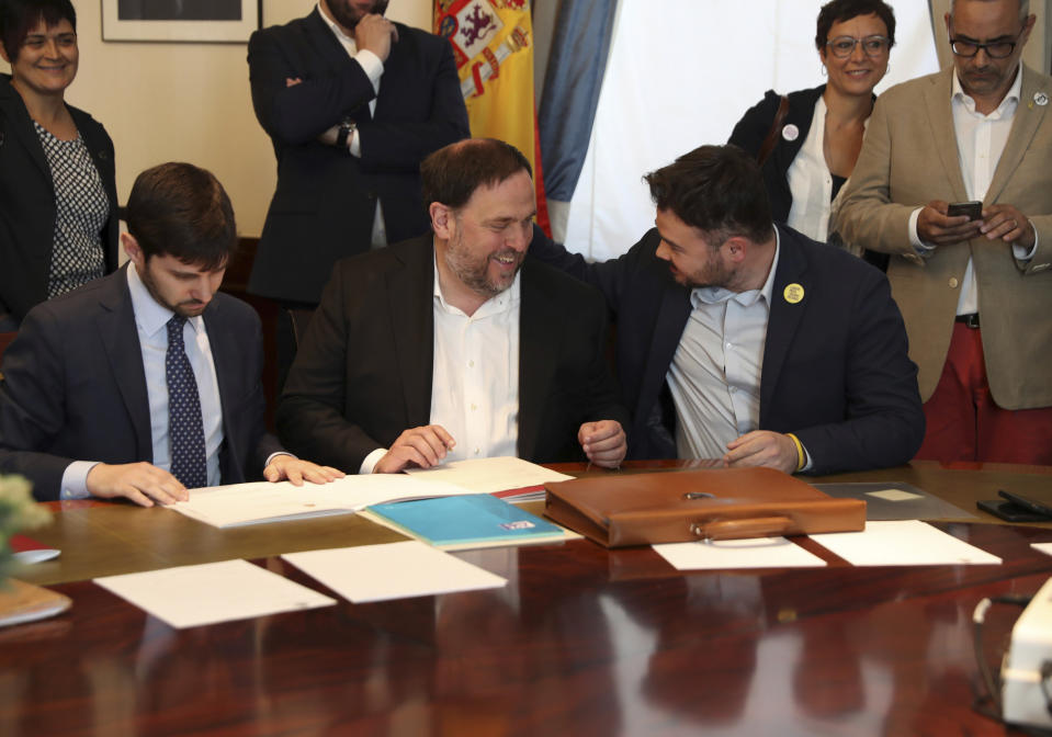 The leader of the Catalonian ERC party Oriol Junqueras, center, speaks with the ERC spokesperson for the parliament Gabriel Rufian, right, at the Spanish parliament in Madrid, Spain, Monday May 20, 2019. The five separatist leaders on trial for Catalonia's 2017 secession attempt who were elected to the Spanish Parliament in April 28 elections have been escorted by police to pick up their official parliament credentials. The Supreme Court is allowing the five politicians to get their credentials on Monday and attend the opening session of the new Parliament on Tuesday. (J.J. Guillen/Pool Photo via AP)