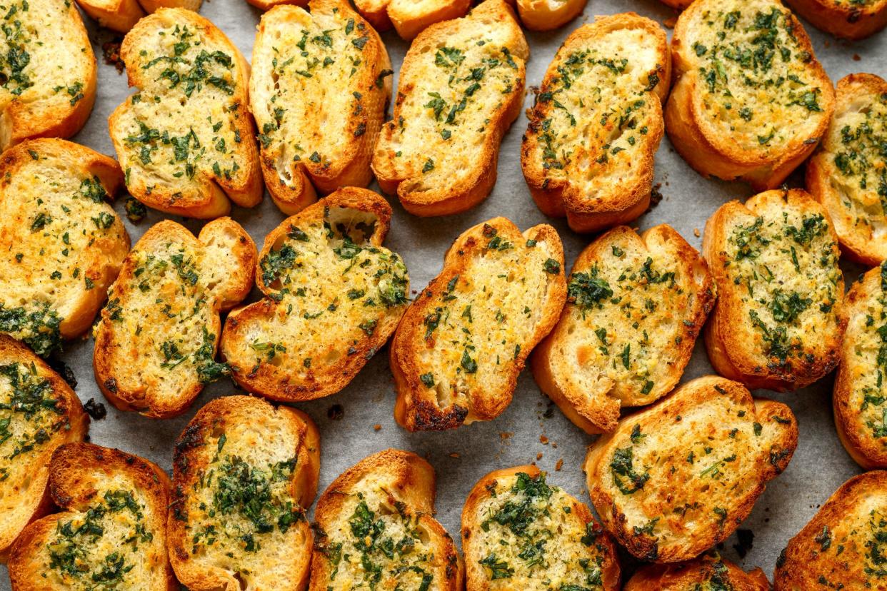 Top view of several pieces of garlic bread on a sheet of wax paper