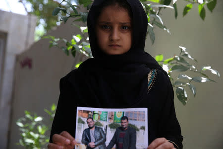 Farah, daughter of Walid al-Abidi, who was killed by Islamic State militants at Kirkuk road, holds his picture, in Kerbala, Iraq July 5, 2018. REUTERS/Abdullah Dhiaa al-Deen/Files