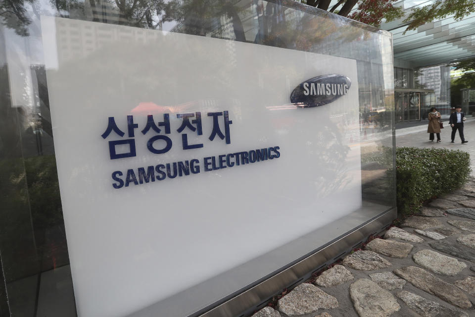 People walk near the logo of the Samsung Electronics Co. at its office in Seoul, South Korea, Thursday, Oct. 31, 2019. Samsung Electronics said it operating profit for the last quarter fell by nearly 56%, with its robust sales of smartphone, displays and TVs offset by a continuously weak market for computer chips. (AP Photo/Ahn Young-joon)