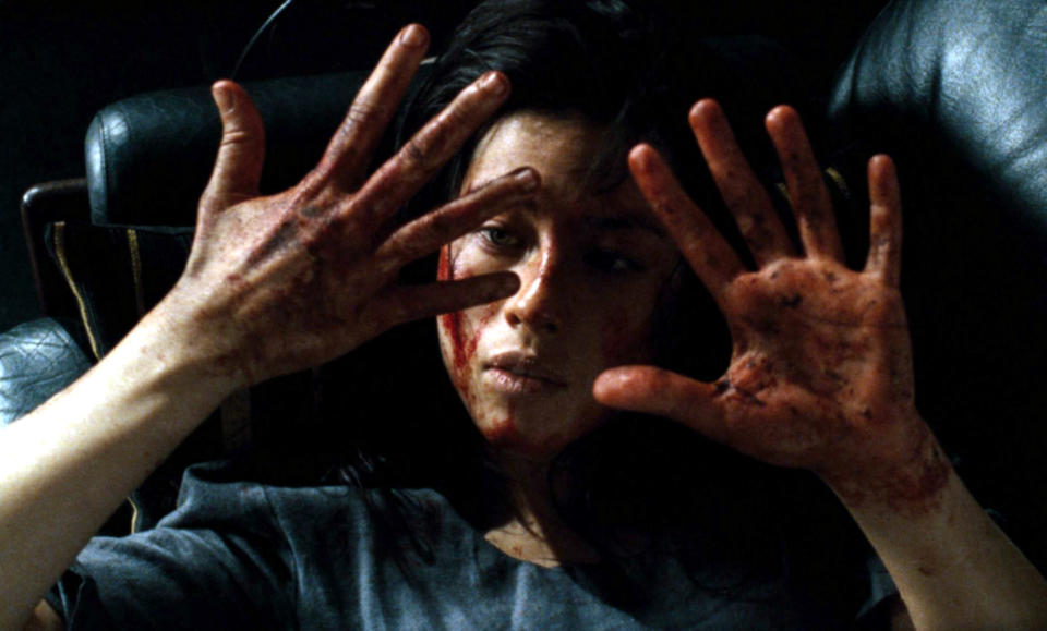 A woman stares at her hands, which are covered in blood