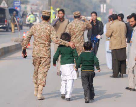 A soldier escorts schoolchildren after they were rescued from the Army Public School that is under attack by Taliban gunmen in Peshawar, December 16, 2014. REUTERS/Khuram Parvez