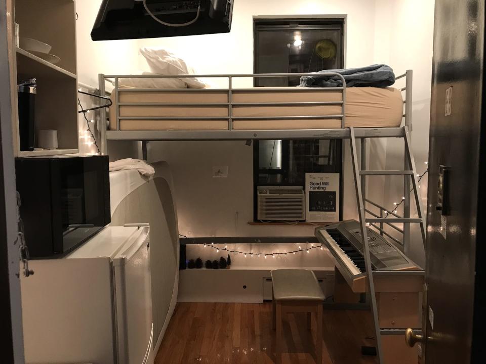 the Inside of Axel Webber's apartment with a lofted bed, mini fridge and piano