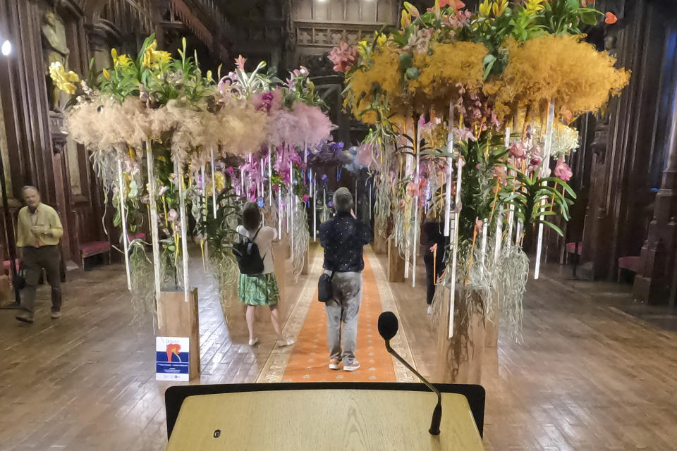 Visitors photograph the interior of City Hall decorated with flowers in Brussels, Belgium, Friday Aug. 11, 2023. Belgium has a century-old fling with surrealism and is always proud to flaunt it. This year they're combining it with an annual flower show in Brussels. (AP Photo/Mark Carlson)