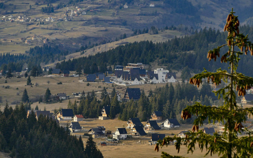 The afternoon sun illuminates hotels and houses in Vlasic, a ski resort affected by unusual warm weather in Bosnia, Tuesday, Jan. 3, 2023. The exceptional wintertime warmth is affecting ski resorts across Bosnia, prompting tourism authorities in parts of the country to consider declaring a state of natural emergency. (AP Photo/Almir Alic)