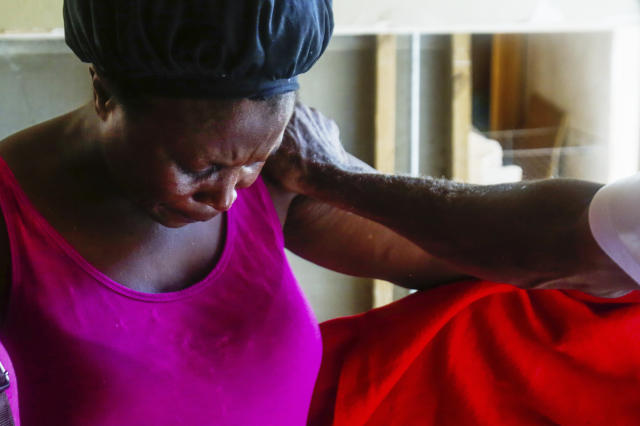In this Sept. 16, 2019 photo, Remelda Thomas bows her head in prayer in her home in McLean's Town Cay, Grand Bahamas Island, Bahamas. Thomas said she lost eight family members in the storm. While sleeping one night after the storm the wind was blowing and the tarp over the hole in her roof was snapping and it brought back the fear from Hurricane Dorian. (Chris Day/University of Florida via AP)