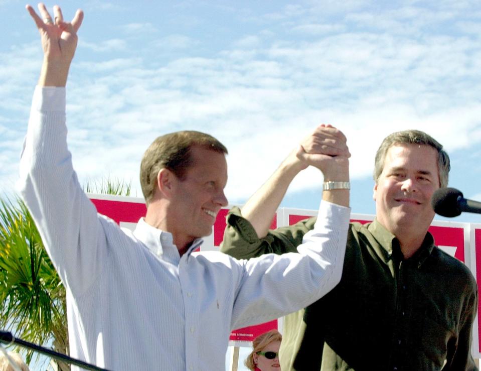 Lt. Gov. Frank Brogan, left, holds up four fingers for four more years of the Bush-Brogan administration as he joins hands with Gov. Jeb Bush during a political rally, Friday, Nov. 1, 2002, in Panama City. Bush and Brogan, both education reformers, stopped in Panama City on their north Florida campaign bus tour.