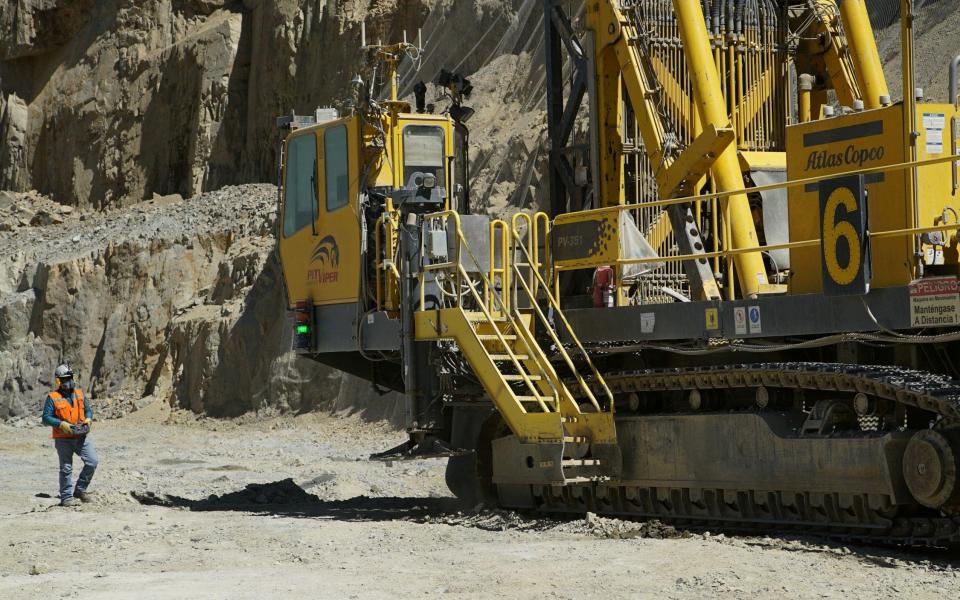 A worker walks near a drill rig in a pit at Anglo American's Los Bronces copper mine in Chile