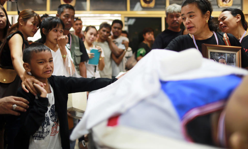 Natdanai Chuchan, an 8-year old boy son of Prakong Chuchan, a protester who was killed in the bomb blast on Friday, cries after seeing the body of his father, center, before a memorial service at Rama hospital in Bangkok, Thailand Sunday, Jan. 19, 2014. On Friday, a grenade hurled at a crowd of marching demonstrators in another part of Bangkok killed one man and wounded dozens of people, police said. (AP Photo/Wason Wanichakorn)