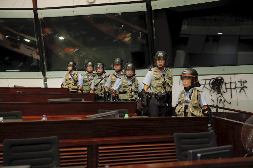 Police officers with protective gear retake the meeting hall of the Legislative Council in Hong Kong, during the early hours of Tuesday, July 2, 2019. Hundreds of protesters in Hong Kong swarmed into the legislature's main building Monday night, tearing down portraits of legislative leaders and spray-painting pro-democracy slogans on the walls of the main chamber as frustration over a lack of response from the administration to opposition demands boiled over. (AP Photo/Kin Cheung)