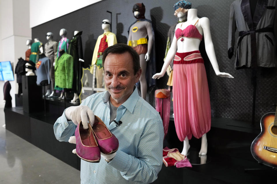 James Comisar holds a pair of shoes once used by actor Barbara Eden in the television show, "I Dream of Jeannie", Thursday, April 27, 2023, in Irving, Texas. A dizzying number of props, sets, and costumes from television shows beloved by generations of viewers will be sold at auction next month. The collection James Comisar has spent over 30 years amassing includes "The Tonight Show" set Johnny Carson gave him after retiring, the timeworn living room from "All in the Family," and the bar where Sam Malone served customers on Cheers. (AP Photo/Tony Gutierrez)