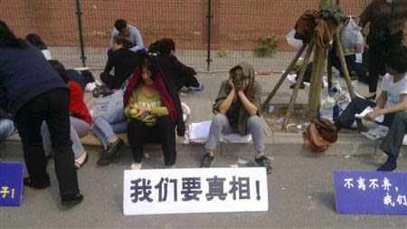 Family members of passengers aboard the missing Malaysia Airlines flight MH370 gather during a sit-in protest outside the Malaysian embassy in Beijing, April 25, 2014. The sign in white reads, "We want the truth". REUTERS/Courtesy of family members/Handout via Reuters