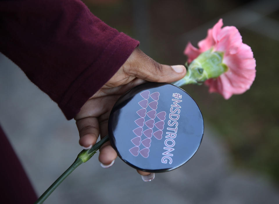 &nbsp;A student holds a flower and a button that reads,' #MSDSTRONG,' as she arrives for classes at Marjory Stoneman Douglas High School for the first time since the shooting that killed 17 people on February 14 at the school on February 28, 2018 in Parkland, Florida.&nbsp;