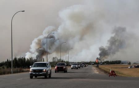 A group of evacuees in a convoy drive in front of smoke from the the wildfires near Fort McMurray, Alberta, Canada, May 6, 2016. REUTERS/Mark Blinch