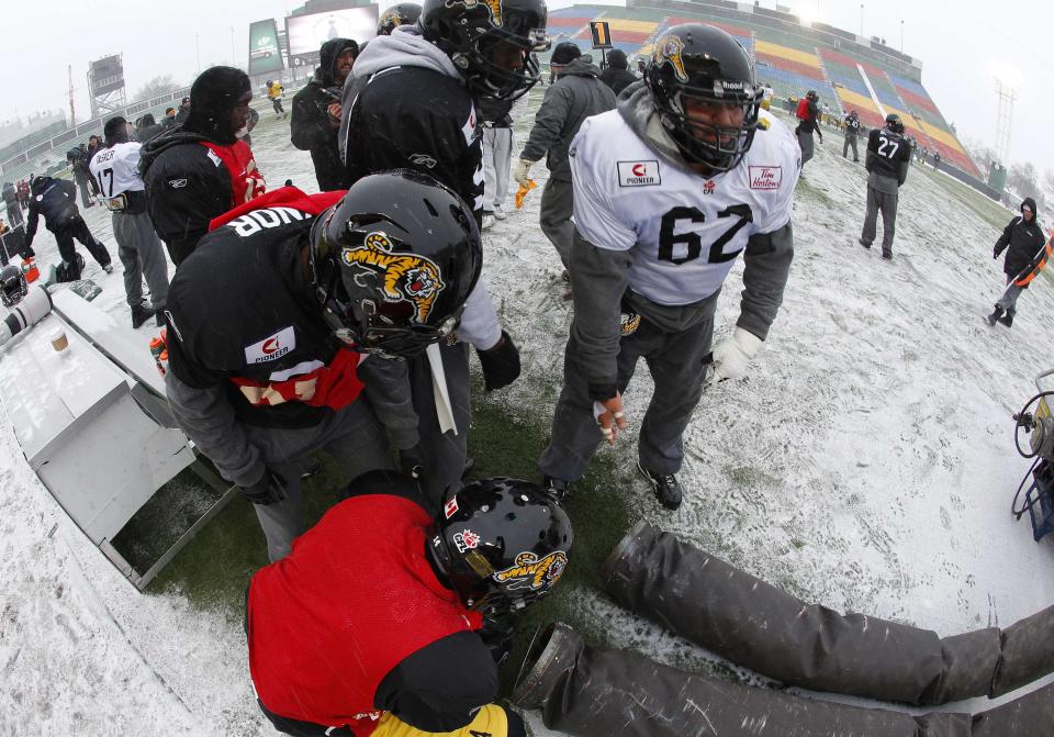 Hamilton Tiger-Cats' Marwan Hage (62) tries to keep warm with his teammates in the bitter cold during their team practice in Regina, Saskatchewan, November 20, 2013. The Saskatchewan Roughriders will play the Hamilton Tiger-Cats in the CFL's 101st Grey Cup in Regina on November 24. REUTERS/Todd Korol (CANADA - Tags: SPORT FOOTBALL)