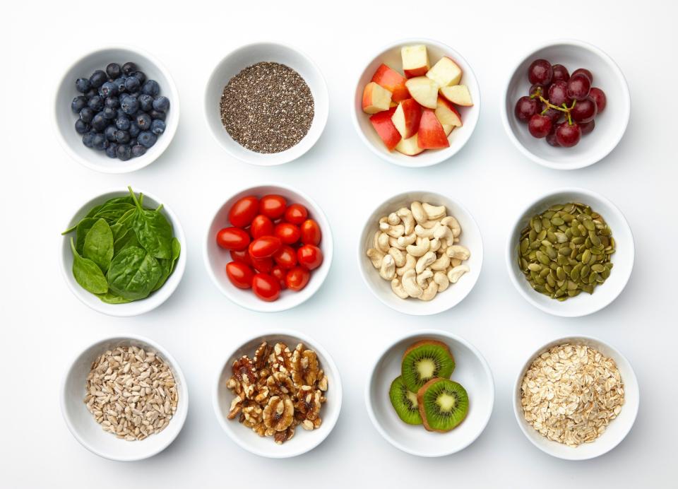 A grouping of various super foods. Blueberries, chia, apples, grapes, spinach, tomatoes, grapes, cashews, pepitas, sunflower seeds, walnuts, kiwi, oatmeal - Getty