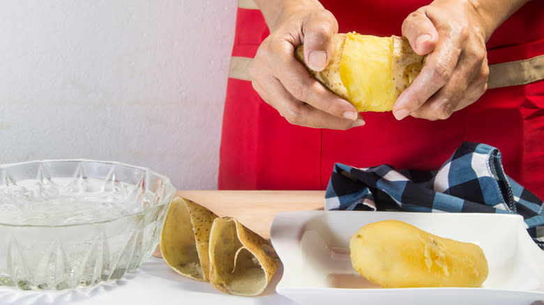 Person removing skin from cooked potatoes