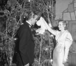 <p>Ginger Rogers looks sophisticated in a slinky white satin evening gown at a Christmas party in Los Angeles. Her dress's silver beading matches the tinsel-strewn tree. </p>