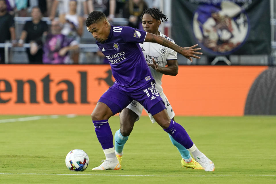 Orlando City's Junior Urso (11) protects the ball from New England Revolution's DeJuan Jones during the first half of an MLS soccer match Saturday, Aug. 6, 2022, in Orlando, Fla. (AP Photo/John Raoux)