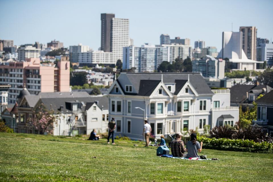 People sit on the grass at Alamo Square Park