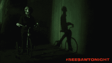 GIF of the scary doll riding a tricycle in the dark