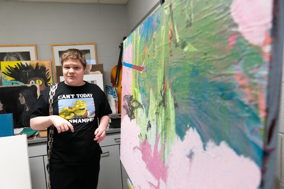 Elijah Holmes, a senior at Washburn Rural, uses one of the large canvases made by Denise Evans for his artwork Friday morning.