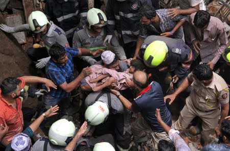 Rescue workers carry a child who was rescued from the rubble at the site of a collapsed building in Mumbai