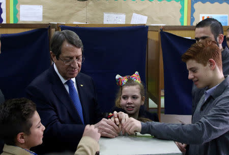 Presidential candidate Nicos Anastasiades casts his vote with some help from his grandchildren, during the second round of the presidential election in Limassol, Cyprus February 4, 2018. REUTERS/Yiannis Kourtoglou