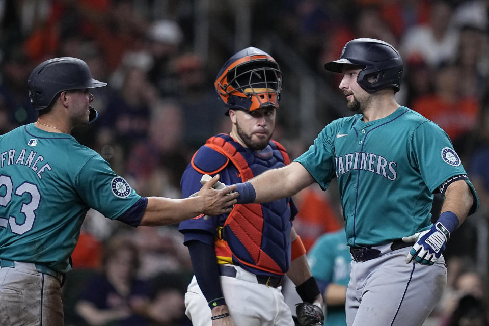 Seattle Mariners' Cal Raleigh, right, is congratulated by Ty France, left, as Houston Astros catcher Victor Caratini, center, looks on after hitting a two-run home run during the sixth inning of a baseball game Saturday, May 4, 2024, in Houston. (AP Photo/Kevin M. Cox)