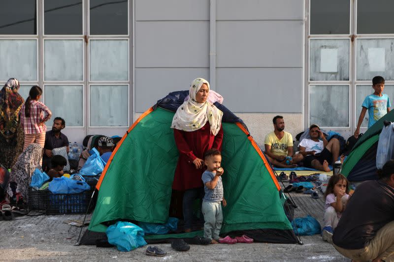 A woman and a child stand outside a tent as refugees and migrants from the destroyed Moria are sheltered near a new temporary camp, on the island of Lesbos
