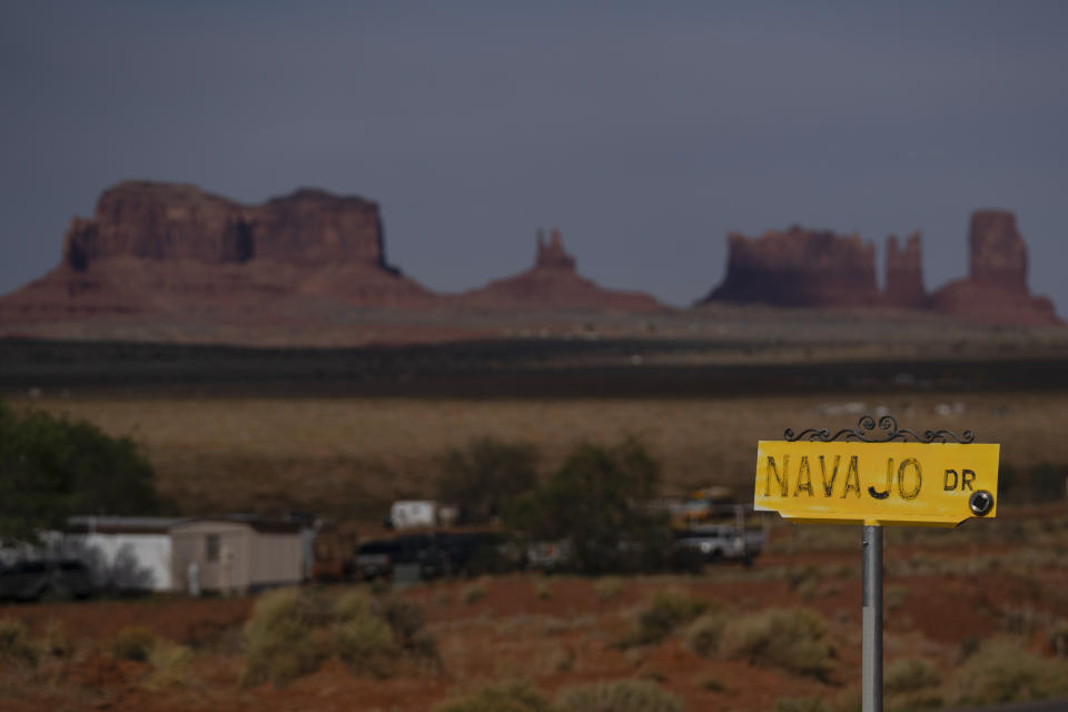 FILE - A sign marks Navajo Drive, as Sentinel Mesa, homes and other structures in Oljato-Monument Valley, Utah, on the Navajo Reservation, stand in the distance, on April 30, 2020. The Supreme Court has ruled against the Navajo Nation in a dispute involving water from the drought-stricken Colorado River. States that draw water from the river — Arizona, Nevada and Colorado — and water districts in California had urged the court to decide for them, and that's what the justices did in a 5-4 ruling. (AP Photo/Carolyn Kaster, File)