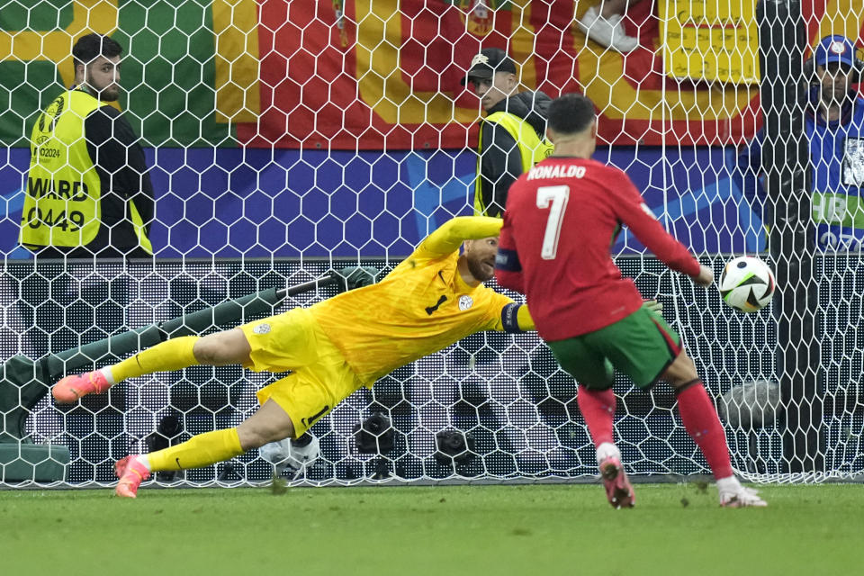 Slovenia's goalkeeper Jan Oblak blocks a penalty kick by Portugal's Cristiano Ronaldo (7) during a round of sixteen match at the Euro 2024 soccer tournament in Frankfurt, Germany, Monday, July 1, 2024. (AP Photo/Ebrahim Noroozi)